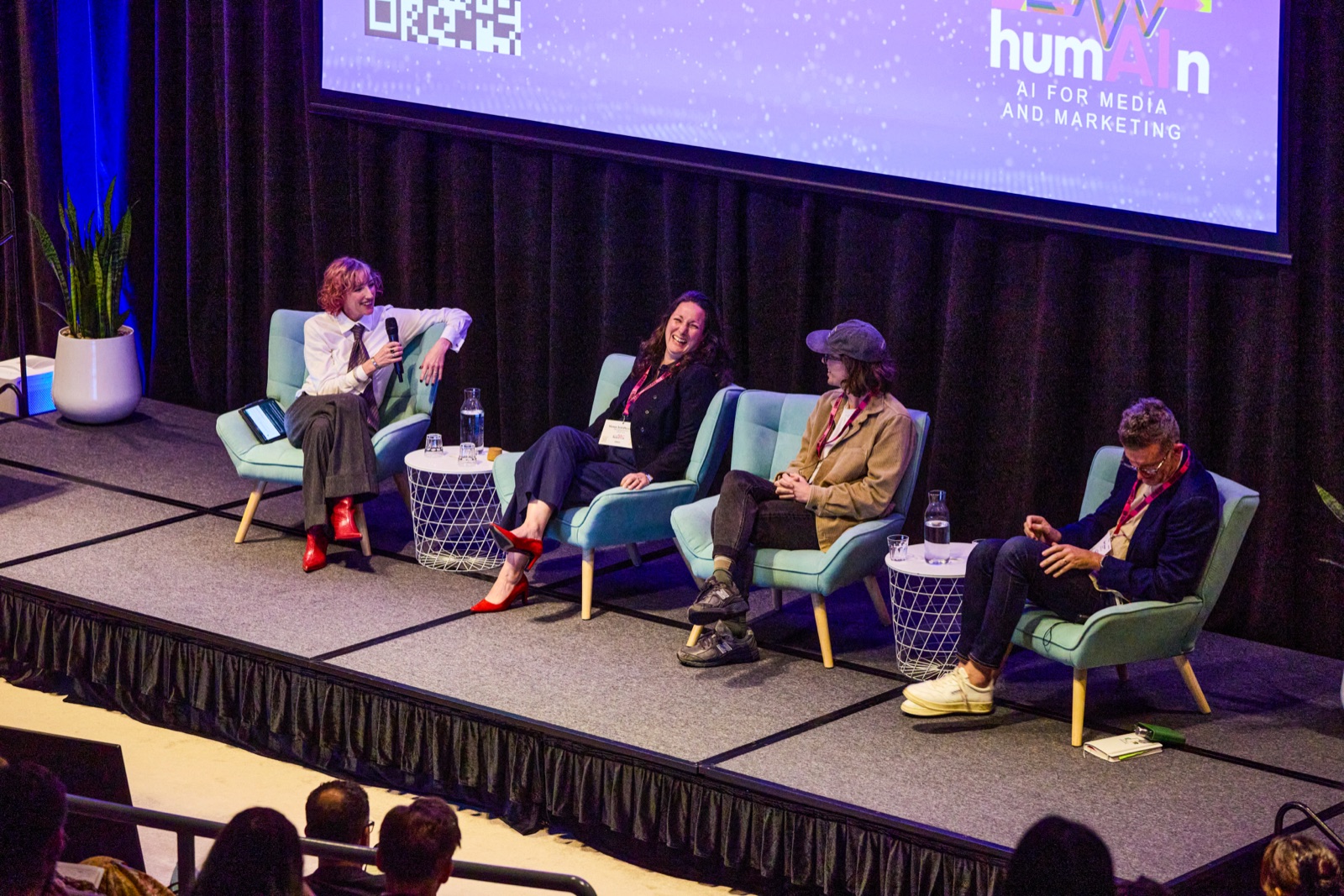 Four-person panel discussion on stage with humAIn branding on the screen behind