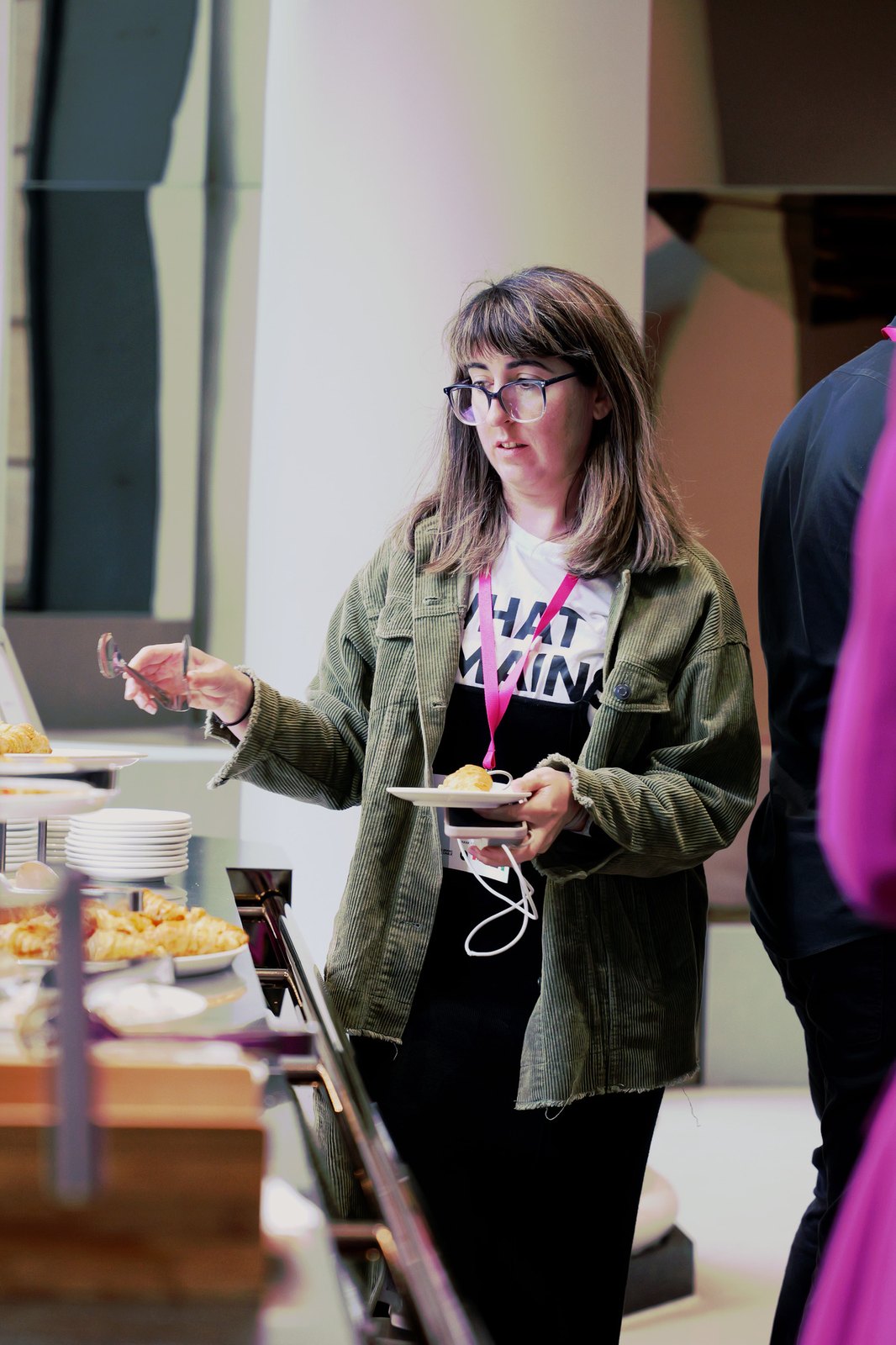 A woman in glasses and a green jacket at the catering table