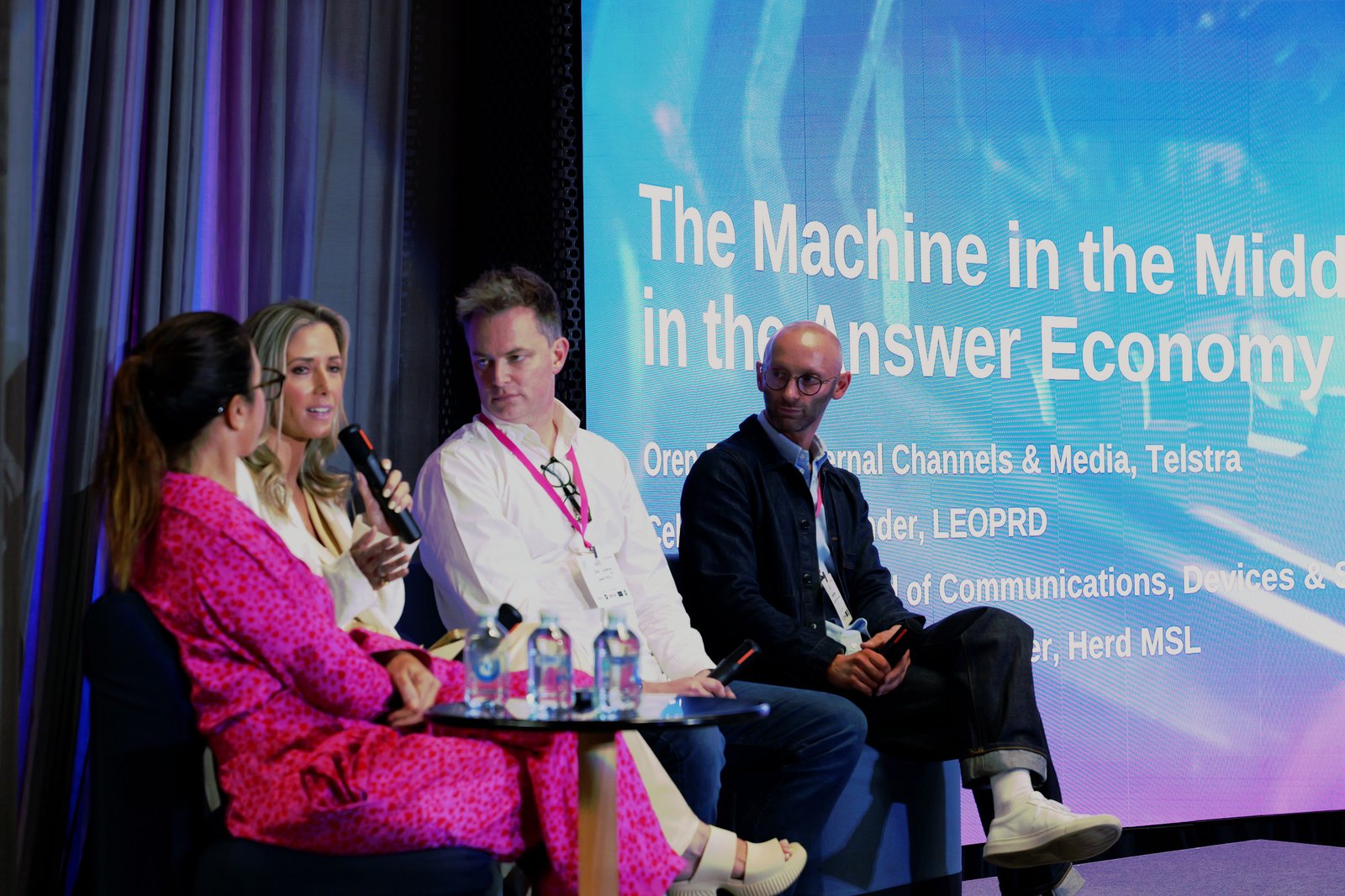 A panel in conversation in front of a slide titled "The Machine in the Middle in the Answer Economy"