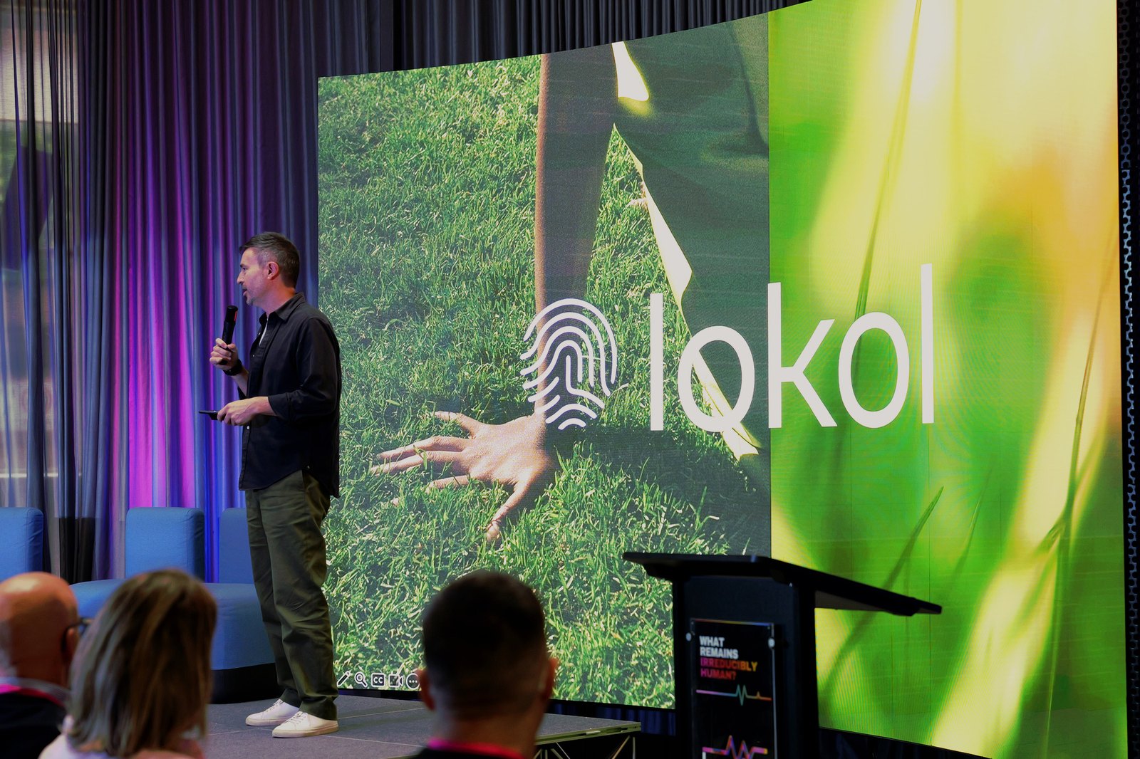 A man speaking with a microphone in front of a lokol slide