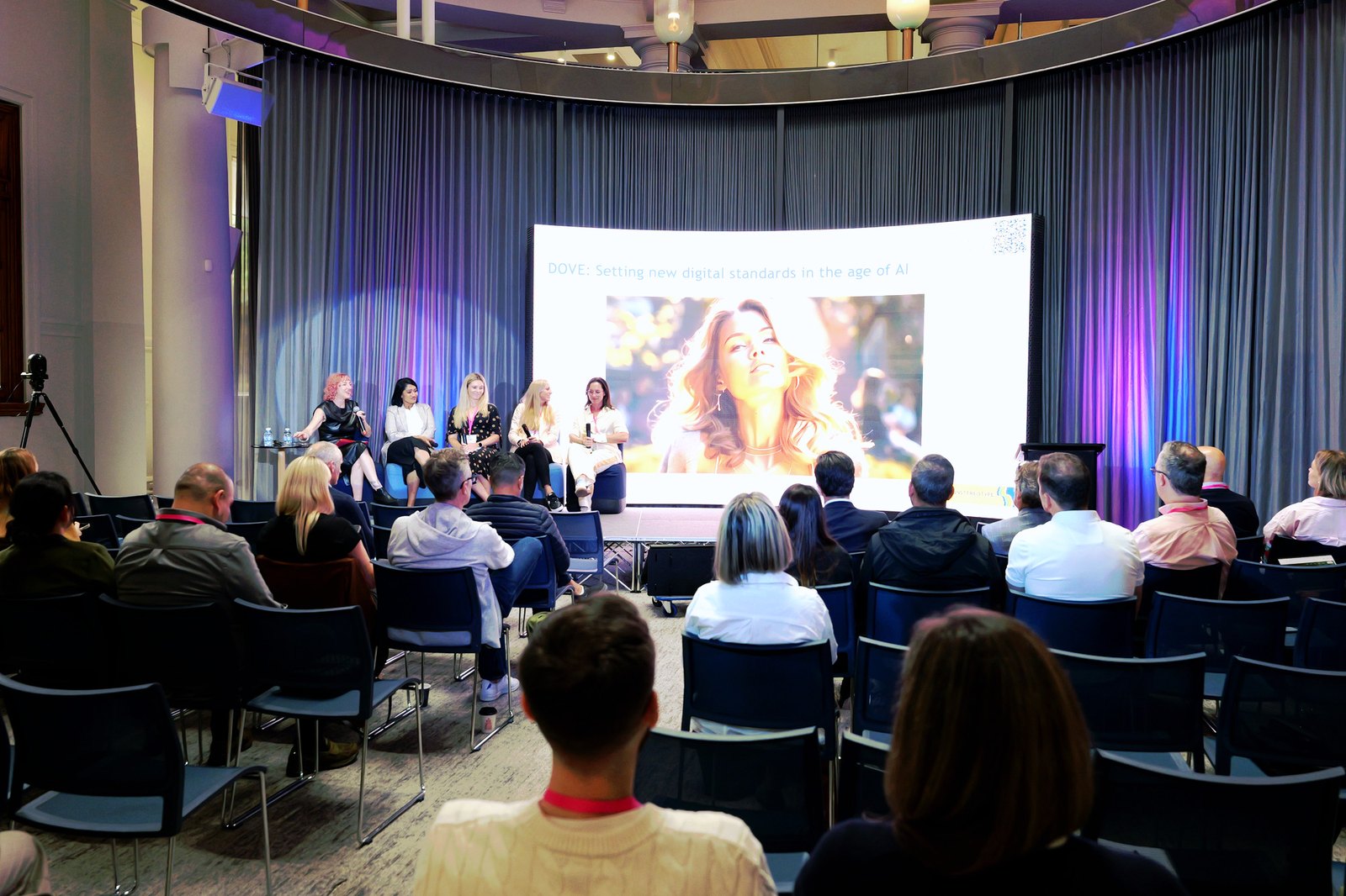 Wide view of a panel on stage in front of a slide about setting new digital standards in the age of AI