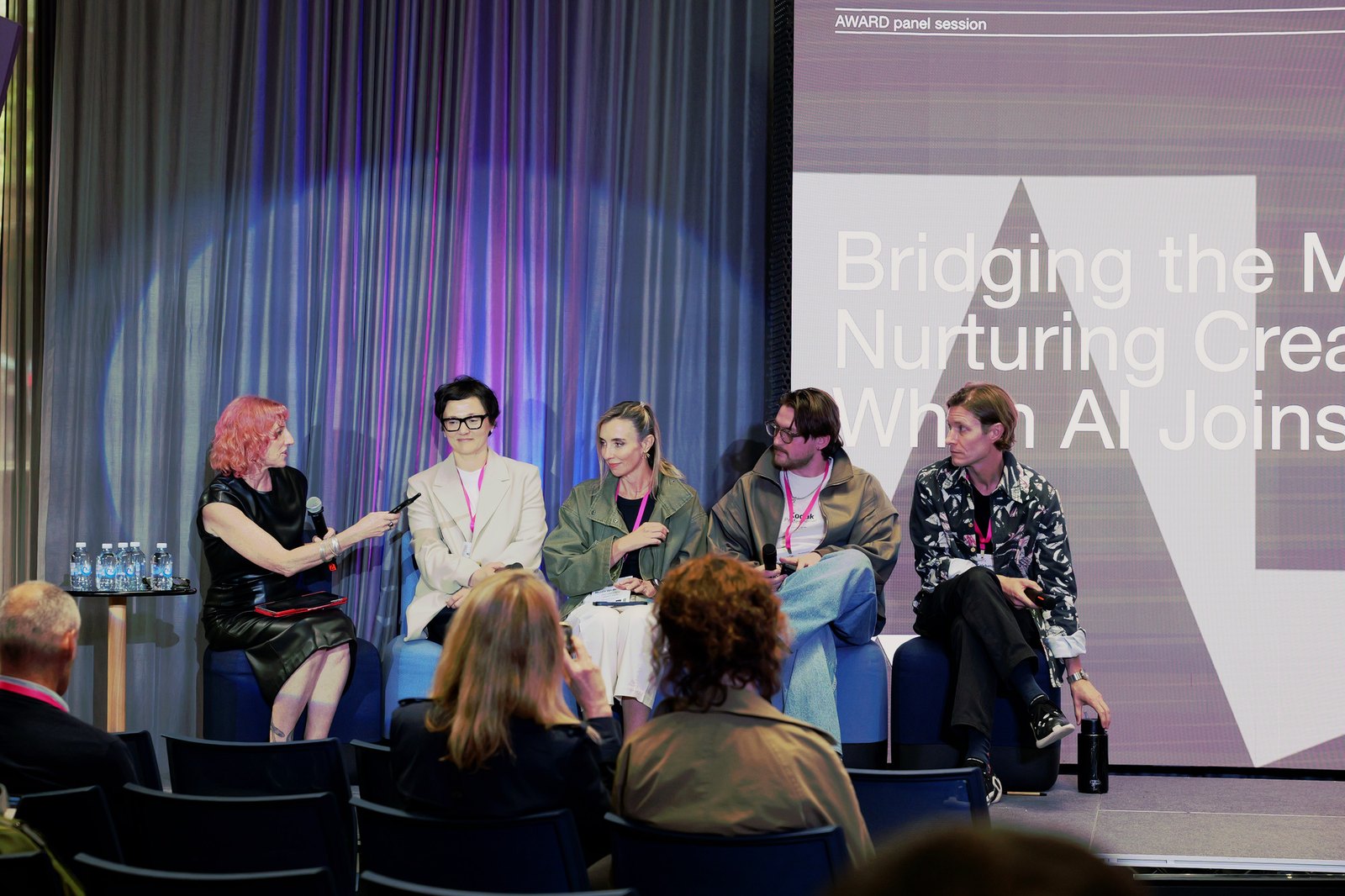 Cat McGinn moderating a panel on stage in front of a slide titled "Bridging the Missing Rung"