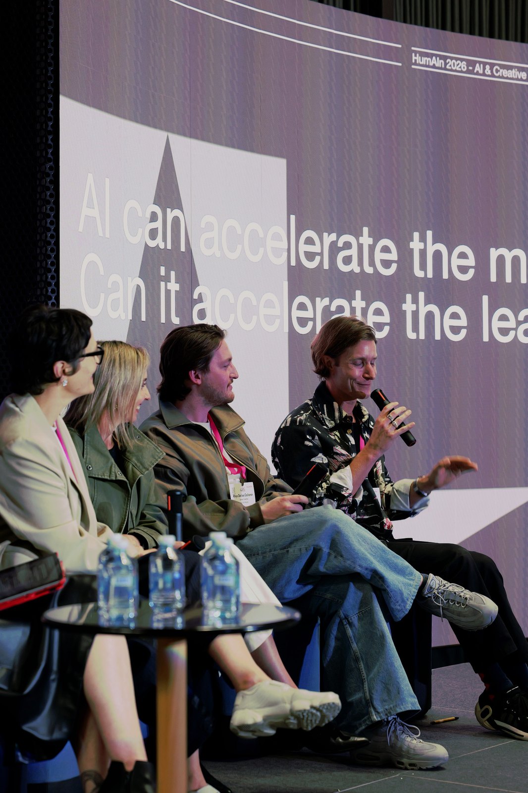 A panellist speaking in front of a slide reading "AI can accelerate the making"