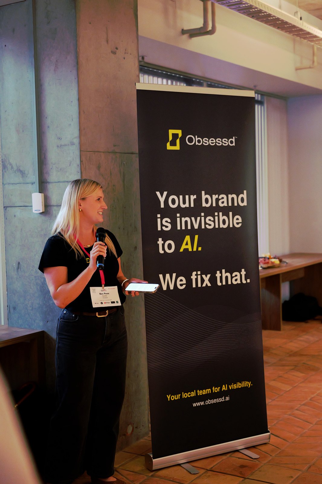 Bec Penn, Founder of Obsessd, speaking beside the Obsessd banner